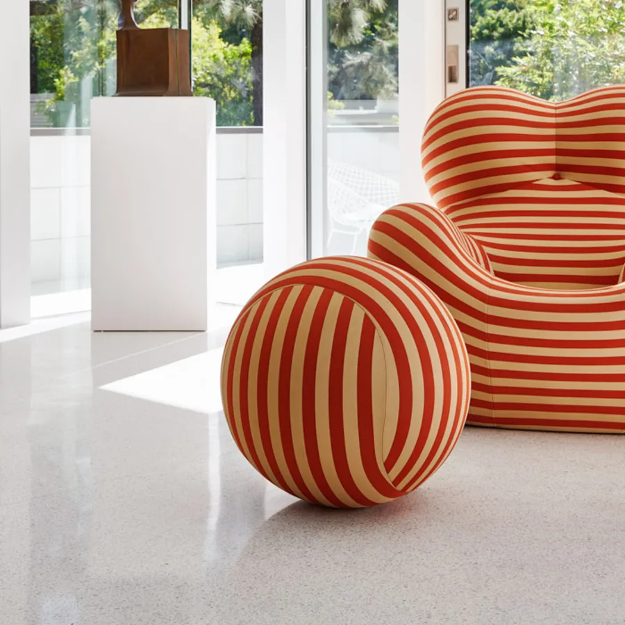 A red and white striped armchair and its matching ball ottoman in a white room at 1061 Loma Vista.