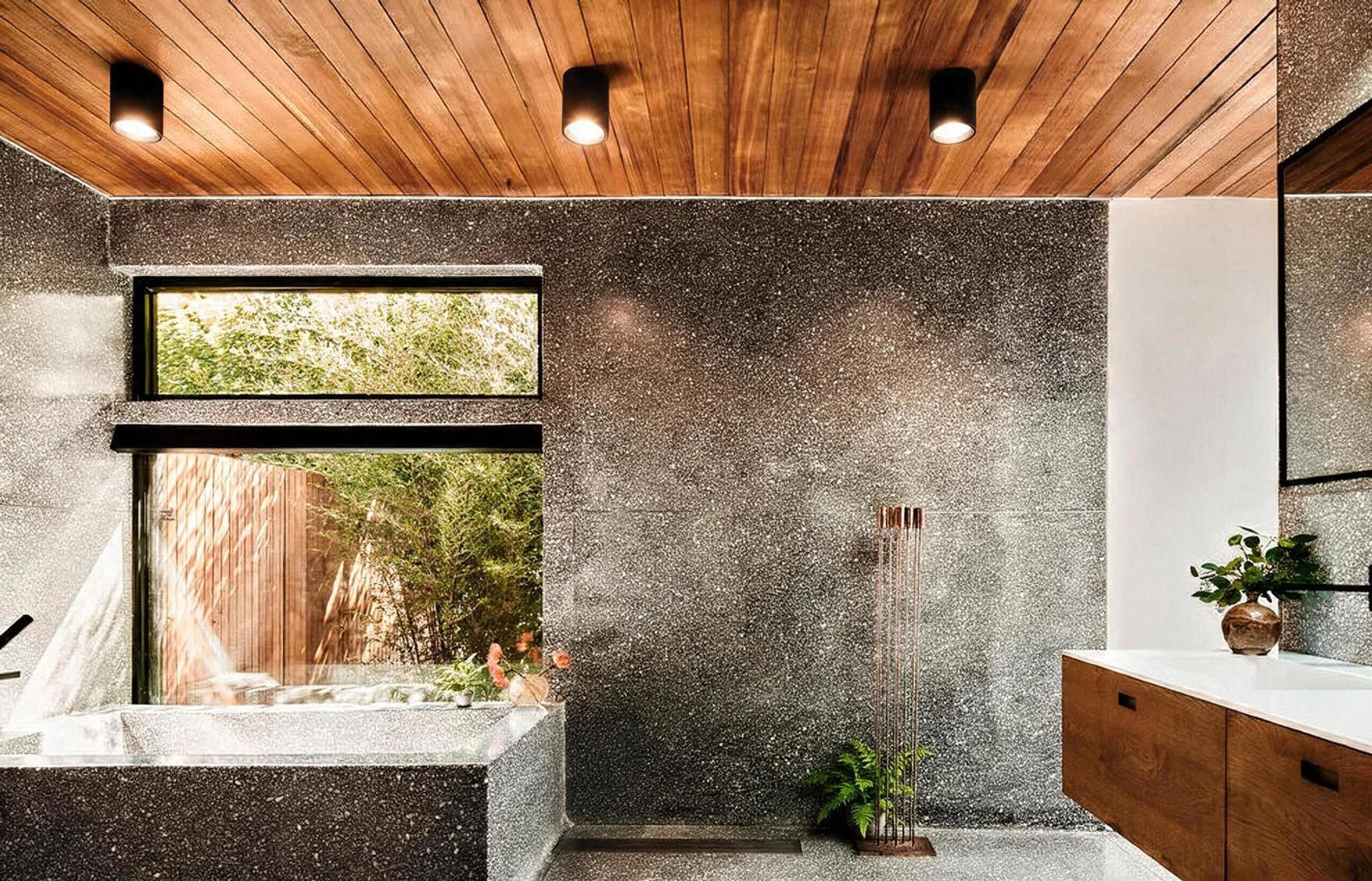 The bathtub in terrazzo under the timber ceiling, a window onto greenery.