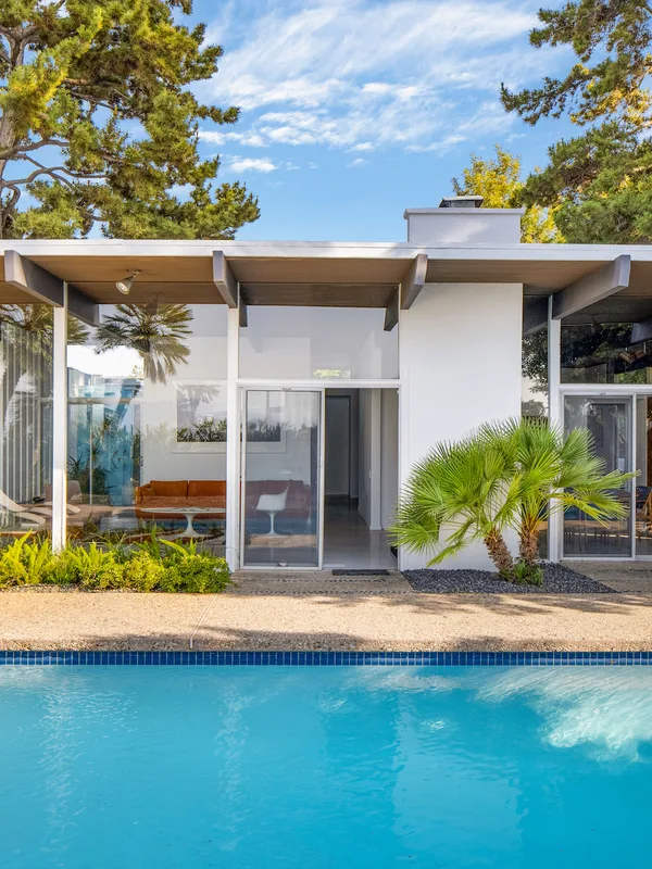 The Calvin House: wide eaves and glass walls over the pool, in afternoon light.
