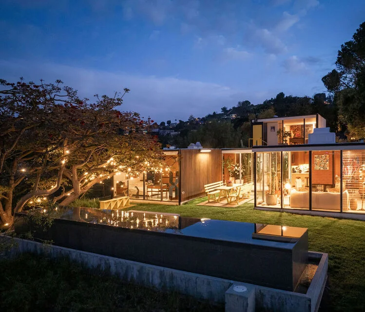 The house lit at dusk above the pool.