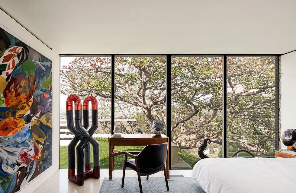 A bedroom under the trees, a sculpture by the desk.