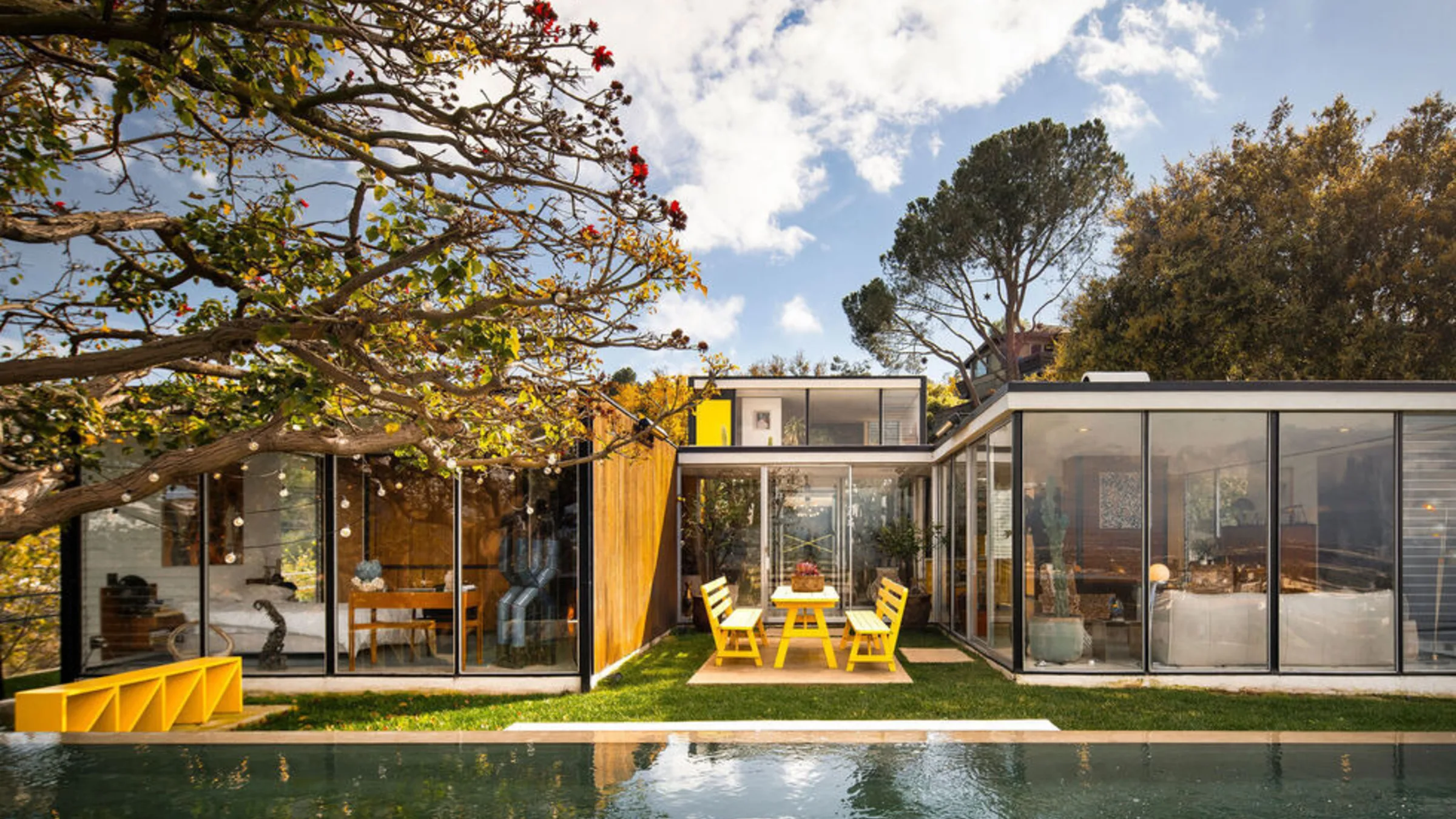 Casa Kuderna: Craig Ellwood's steel-and-glass pavilions beyond the lap pool, a yellow chair on the lawn.