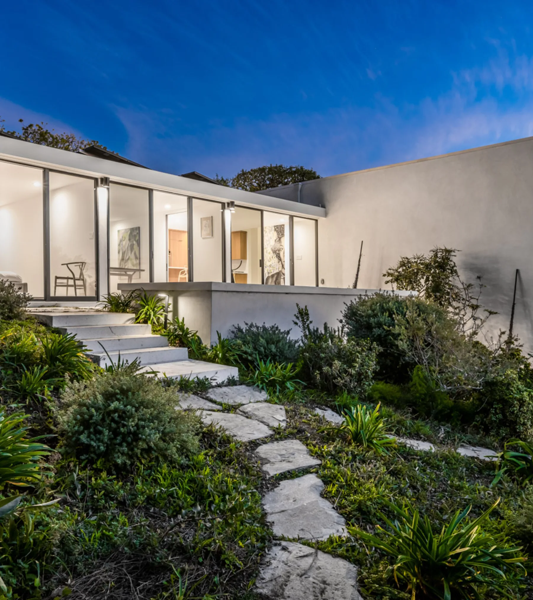The Cool Oak House, Malibu, its walls of glass glowing at nightfall.
